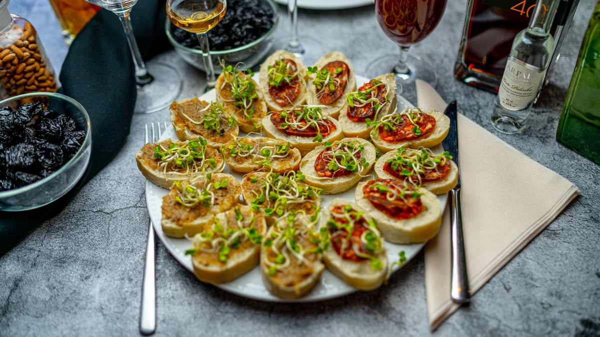A gourmet appetizer platter featuring delicious bruschetta with sprouts, paired with a selection of wines.